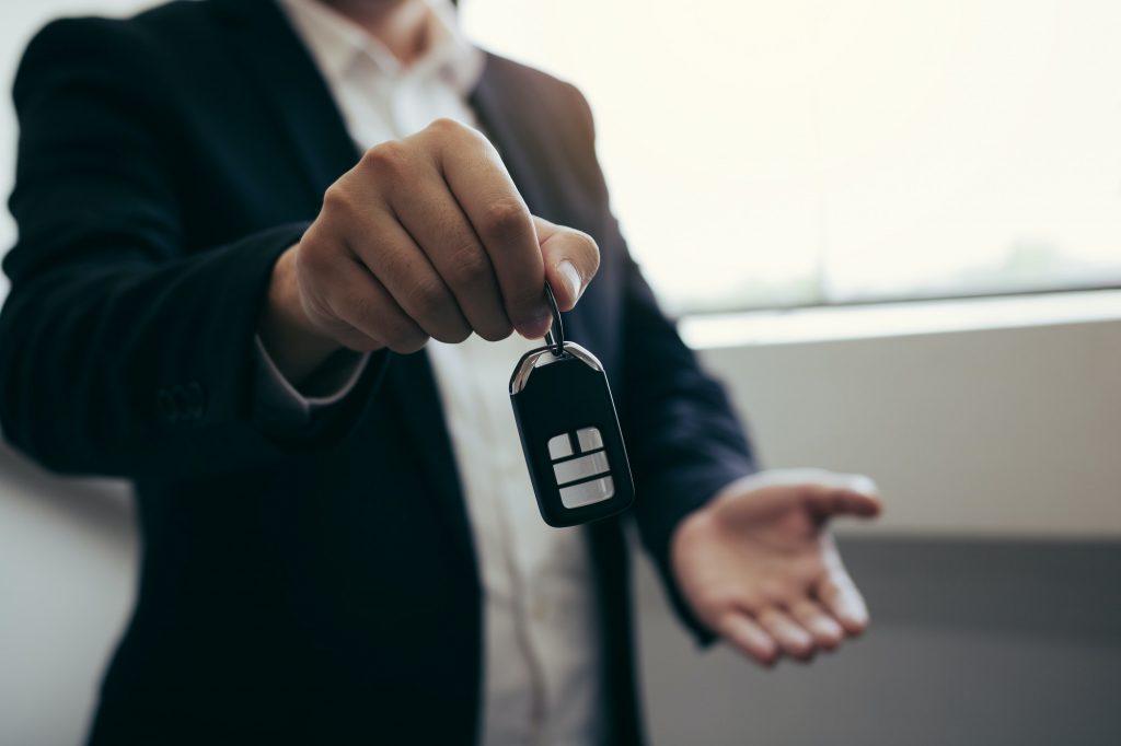 Car sales agent are car keys with the idea of buying a new car.